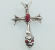 Stříbrný kříž s lebkou a korálem.